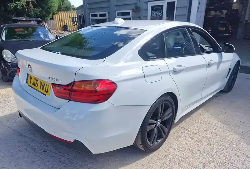 Rear shot of white BMW car expertly refurbished after an accident outside a garage workshop